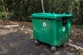 Large green recycle bin on the street of a park