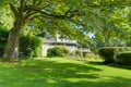 Large green summer authentic back yard with grey brown large house.