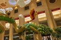 A large green and yellow dragon and a red and yellow bird and clouds hanging from the ceiling surrounded by lush green trees