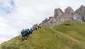 Large group of climbers and two mountain guides hiking towards the start of a climb in the Dolomites