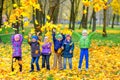 Group of friends playing and having fun in a beautiful autumn park, throwing leaves and laughing Royalty Free Stock Photo