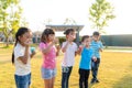 Large group of happy Asian smiling kindergarten kids friends playing blowing bubbles together in the park on the green grass on Royalty Free Stock Photo