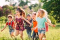 Large group of kids, friends boys and girls running in the park on sunny summer day in casual clothes . Royalty Free Stock Photo