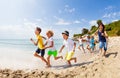 Large group of kids run on a beach along the sea Royalty Free Stock Photo