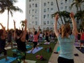 Large group of People raising arms in the air as they do Crescent Lunge yoga pose