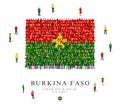 A large group of people are standing in green, yellow and red robes, symbolizing the flag of Burkina Faso