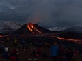 Large group of people watching a volcanic eruption at Fagradalsfjall with lava ejection, flowing streams of glowing lava.