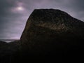 Large grunge boulder and the sun against overcasting cloudy sky backgrounds