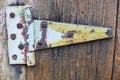 Large, grungy painted metal hinge on old wooden door