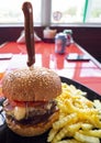 A large hamburger with French fries with a knife on a black plate on a red table in a biker cafe in Greece Royalty Free Stock Photo