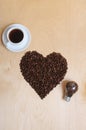 Large heart made of coffee beans, cup of coffee and bulb with coffee beans inside on a light wooden background, top view Royalty Free Stock Photo