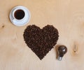 Large heart made of coffee beans, cup of coffee and bulb with coffee beans inside on a light wooden background, top view Royalty Free Stock Photo