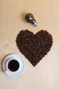 Large heart made of coffee beans, cup of coffee and bulb with coffee beans inside on a light wooden background, top view Royalty Free Stock Photo