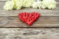 A large heart of raspberries is laid out on a wooden background. Inside there is the flower. Side view. It is an unusual Royalty Free Stock Photo