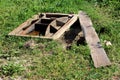 Large heavy custom made rectangle cast metal partially rusted manhole cover next to open manhole temporarily covered with wooden