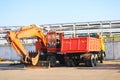 A large heavy yellow orange truck with a trailer, a dump truck and an excavator with a ladle are parked in a row at a construction Royalty Free Stock Photo