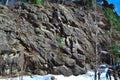 Large high rough climbing rock Vityaz in Siberian forest with conifers in winter in the light of sun. People below. Snow