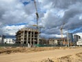 A large, high unfinished new building that is being built with the help of a construction industrial high-rise tower crane Royalty Free Stock Photo
