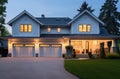 a large home at dusk near a brick garage