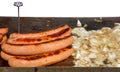 Large hot dog sausages grilling next to chopped onions on an outdoor bbq grill Royalty Free Stock Photo