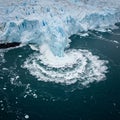 A large ice formation is collapsing into the ocean, creating splashes and circular wave Royalty Free Stock Photo