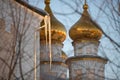 Large icicles hang from the roof on the background of the golden domes of the Christian church at a sunset Royalty Free Stock Photo