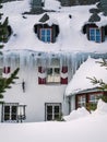 Large icicles and snow cover on a hotel building during winter in a ski resort