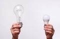 a large incandescent lamp and a small led lamp in the hands on a white background.