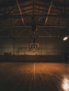 Large Indoor basketball court in darkness, and ball in-mid air flying to hoop in motion. Concept of professional sport