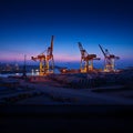 Large industrial cranes operating at port during twilight hours Royalty Free Stock Photo