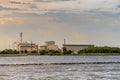 Large industrial factory building side coast of sea in evening and soft orange sunshine with light blue sky Royalty Free Stock Photo