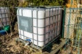 Large industrial liquid tank with a capacity of 1000 liters, 265 gallons with a metal protective grille. Placed in a home garden a