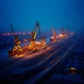 Large industrial port cranes loading ships at dusk near waterfront Royalty Free Stock Photo
