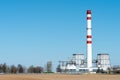 A large industrial smokestack against a blue sky. Red and white pipe in commercial enterprises or power plants