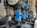 Large industrial water treatment and boiler room. Shiny steel metal pipes and blue pumps and valves Royalty Free Stock Photo