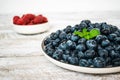 A large iron bowl with juicy ripe blueberries stands on a light wooden table. The bowl is decorated with fresh mint leaves. Royalty Free Stock Photo