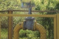 A large iron gray valve and a yellow metal gas pipe behind a fence grid