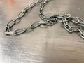A large iron metal strong powerful shiny chain with links lies on an iron industrial table. Hand-held locksmith tools. The