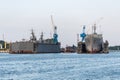 Large iron navy ships in shipyard for repair. Big crane in dockyard. Blue sea harbor Royalty Free Stock Photo