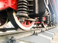 Large iron wheels of a red and black train standing on rails and suspension elements with springs of an old industrial steam Royalty Free Stock Photo
