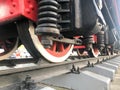 Large iron wheels of a red and black train standing on rails and suspension elements with springs of an old industrial steam Royalty Free Stock Photo