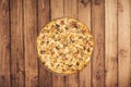 A large Italian family style carbonara pizza viewed from above on a warped wooden table