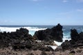 Large, jagged, black lava rock and boulders fronting the Pacific Ocean on the shoreline of Laupahoehoe Point