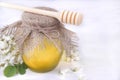 Honey with acacia branch and a spoon for honey on a white wooden background