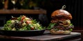 A large juicy burger with a beef patty on a wooden board with a plate of salad. The interior of the evening kitchen