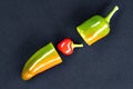 Large juicy multi-colored hot chili pepper cut in half on a black background. In the middle is a small red heart-shaped pepper Royalty Free Stock Photo