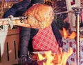 Large juicy pork leg roasting on a spit over an open fire at a farmers market on a winter evening. Royalty Free Stock Photo