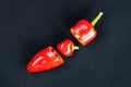 Large juicy red hot chili pepper cut in half on a black background. In the middle is a small red heart-shaped pepper Royalty Free Stock Photo