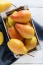 Large juicy yellow pears in a rustic wooden fruit box on a white table Royalty Free Stock Photo