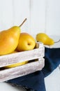 Large juicy yellow pears in a rustic wooden fruit box on a white table. Royalty Free Stock Photo